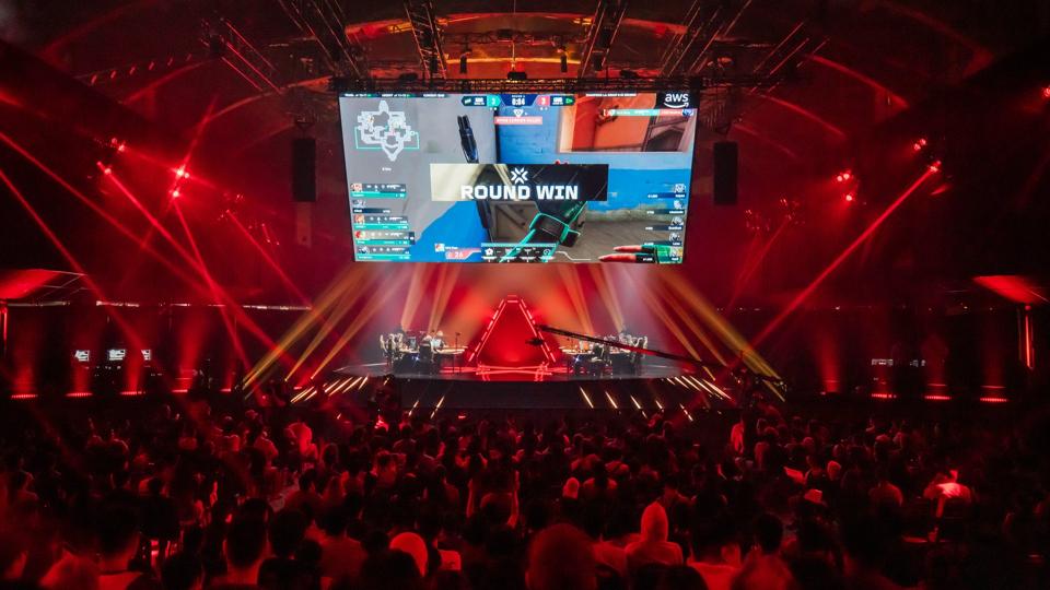 Professional esports team playing a match on a massive brightly lit stage